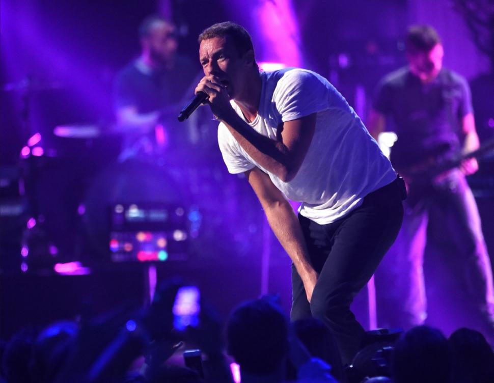Musician Chris Martin of Coldplay performs onstage during the iHeartRadio Music Festival Friday while new gal pal Jennifer Lawrence looks on.